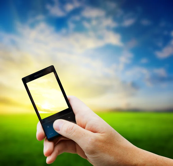 Мобільний телефон в руці і захід сонця в країні — стокове фото