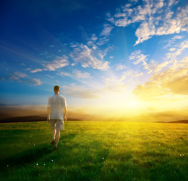 Een man en gebied van voorjaar gras en zonsondergang — Stockfoto