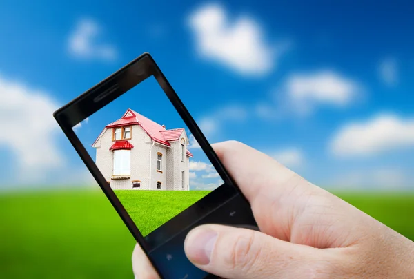Teléfono celular en la mano y la casa —  Fotos de Stock