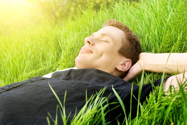 Jonge man ontspannen in voorjaar gras — Stockfoto