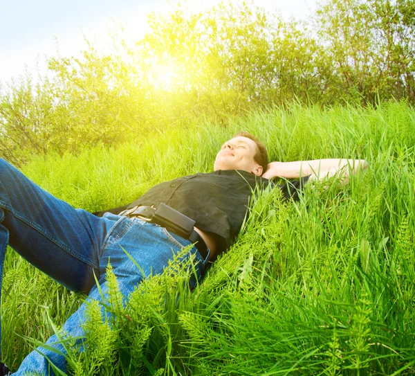 Hombre joven relajarse en la hierba de primavera — Foto de Stock