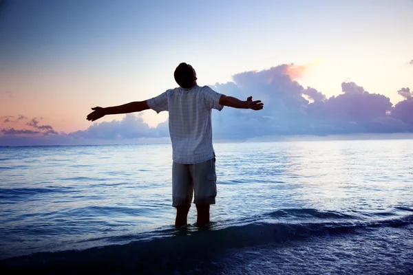 Gelukkig jonge man in zee en zonsopgang Stok Fotoğraf