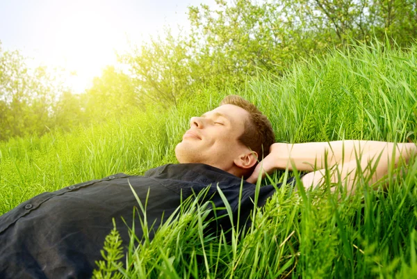 Junger Mann entspannt sich im Frühlingsgras Stockfoto