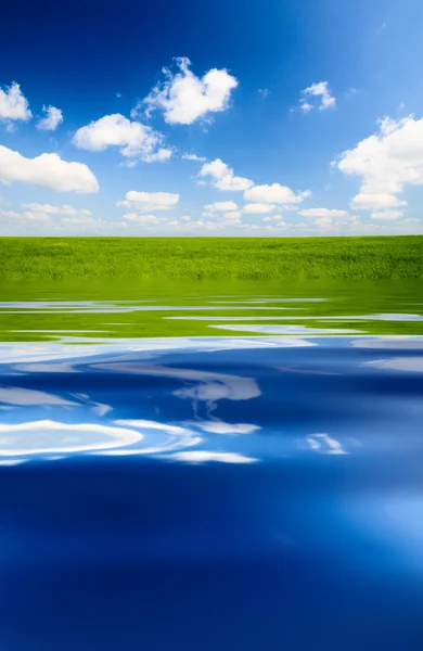 stock image Green field and blue water