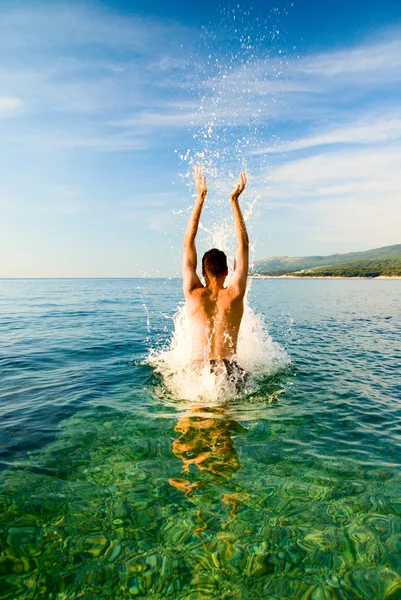 Mann springt aus sauberem Ozeanwasser — Stockfoto