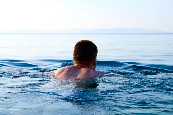 清晨的阳光和在海洋中的游泳男子 — 图库照片