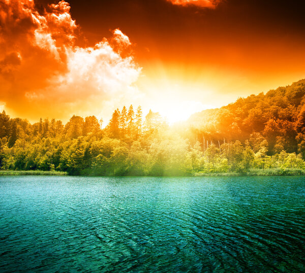 Green water lake in forest and sunset