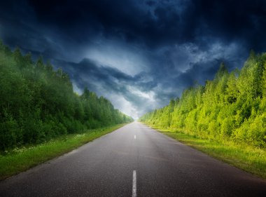 Stormy sky and road in forest clipart