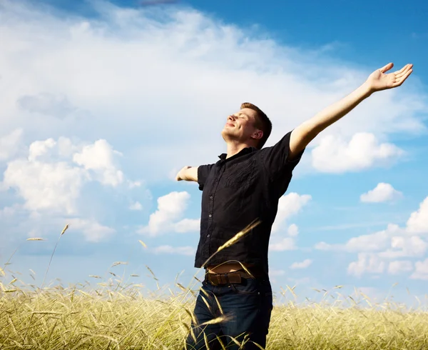Młody człowiek spoczywa na polu pszenicy — Zdjęcie stockowe