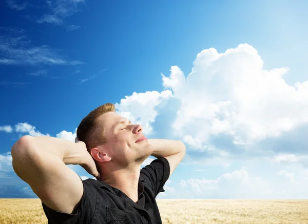 Молодой человек отдыхает на пшеничном поле — стоковое фото