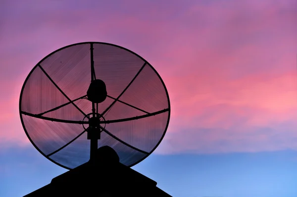 Satelliet schotel silhouet op het dak in avondlucht. — Stockfoto