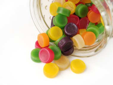 Colorful wine gum lollies falling out of their glass jar, white background clipart