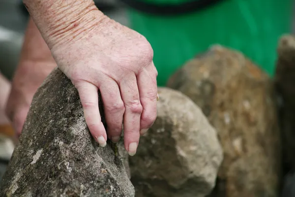 痛みシリーズとの生活 庭の石を移動関節リウマチの年配の女性の手 — ストック写真