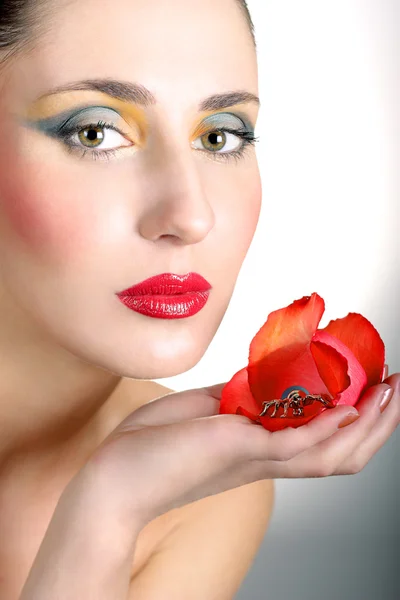 Όμορφη κοπέλα με φωτεινό μακιγιάζ και ένα λουλούδι στο χέρι — Φωτογραφία Αρχείου