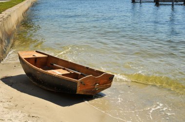 Small sailboat tied off againt a seawall clipart