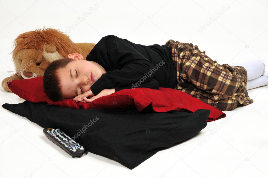 Young boy on pillows on the floor, fallen asleep watching television
