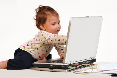 dizüstü bilgisayar ekranında işaret ile oynarken masasında oturan bebek