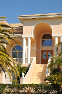 Two story entryway leading to the double doors of this elegant mansion on the bay. The palm trees denote its tropical location. clipart