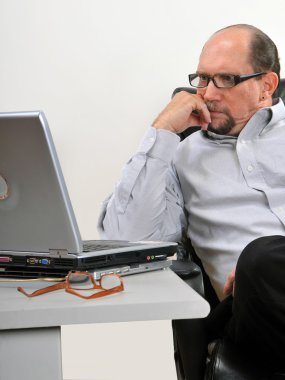 Middle aged man looking at laptop clipart