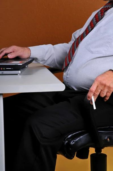 Business man at desk holding a cigarette — Stock Photo, Image