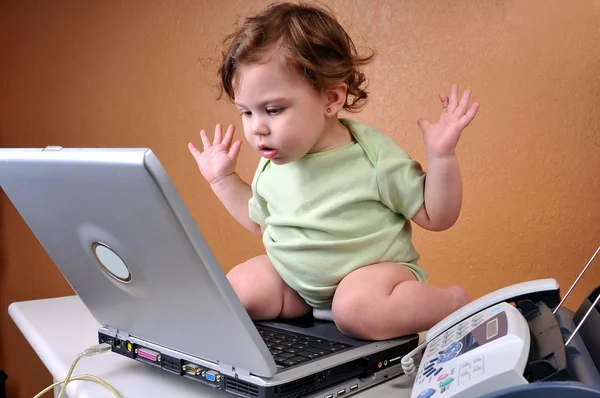 Baby blickt verdutzt auf Laptop Stockbild