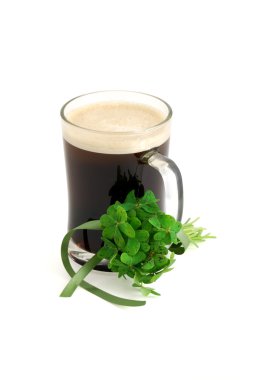 Dark beer in glass and bouquet of false shamrock (Oxalis) with green ribbon on white background clipart