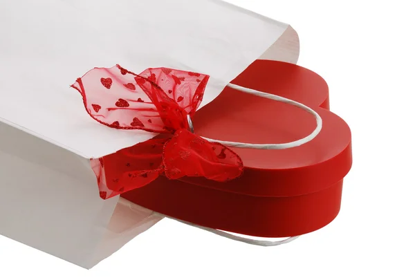 Closeup de saco de presente de papel branco com arco vermelho e pr em forma de coração — Fotografia de Stock