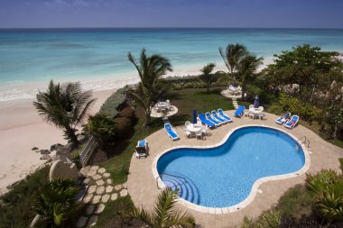 View from a hotel balcony looking out over a swimming pool, beach and ocean waters clipart