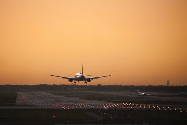 An airplane coming in for a landing as a day draws to a close clipart