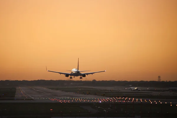 stock image An airplane coming in for a landing as a day draws to a close