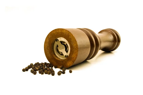 stock image Black peppercorns and a grinder set against a white background