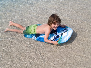 Little boy learning surf in sea clipart