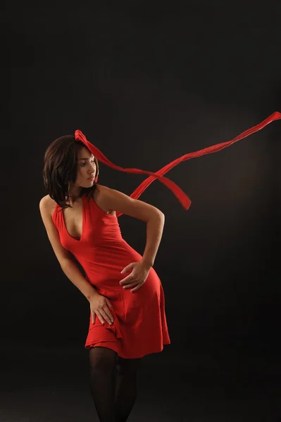在黑色背景的红裙子的美丽亚洲女孩 — 图库照片