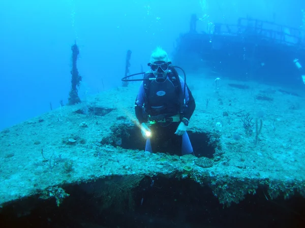 stock image Diver appearing through hole in the Halliburton shipwreck, Utila