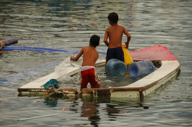 Two small boys desperately baling out a sinking dinghy after a typhoon in the Philippines clipart