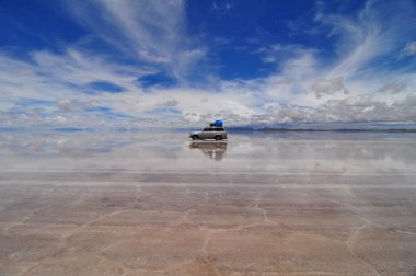 Jeep reflected in flooded Salar de Uyuni salt flats clipart