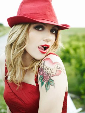 Portrait of a girl in a red hat with a tattoo on his shoulder clipart