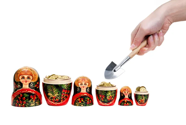 stock image Three Matryoshkas full of coins and hand holding shovel