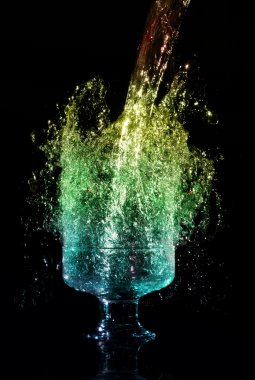 Liquid falling down into the glass with splashes at the black background clipart