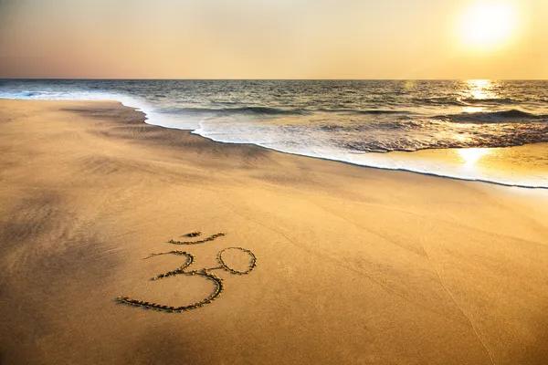 Om símbolo en la playa —  Fotos de Stock