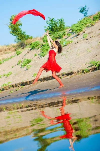 女孩穿着红裙子在海岸上 — 图库照片