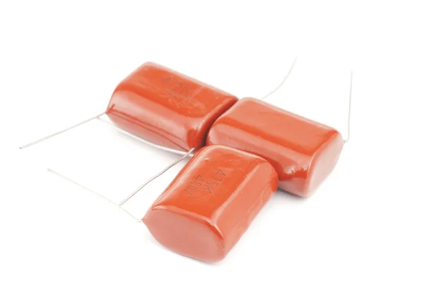 Три помаранчеві конденсатори ізольовані на білому тлі — стокове фото