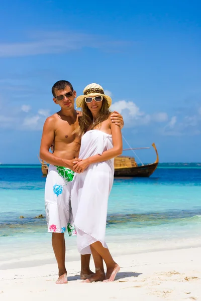 年轻夫妇在背景上海滩上一艘游艇 — 图库照片
