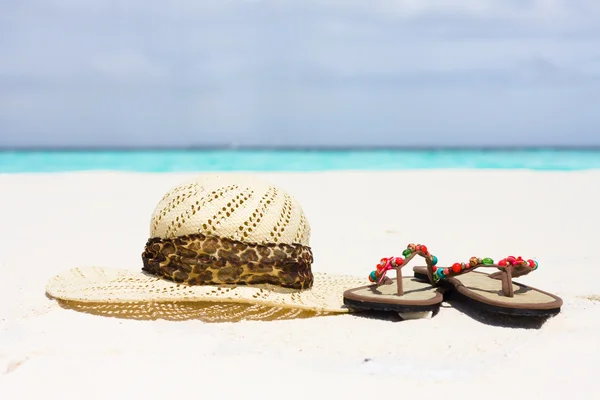 一顶帽子和凉鞋躺在沙滩上 图库图片
