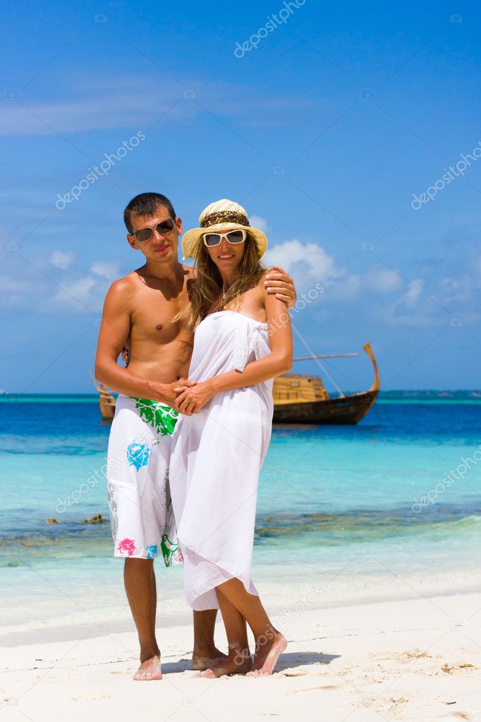 Young couple on a beach on a background a yacht
