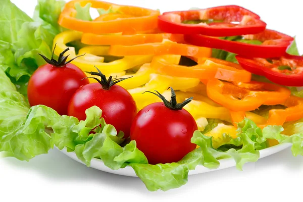 Mix van gekleurde paprika, verse groenten, tomaten op bladeren van groene salade — Stockfoto