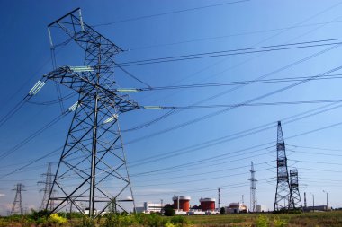 Electrical power lines and nuclear power station under clear blue sky clipart