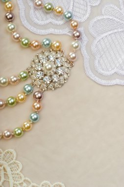 Beautiful pearl necklace with brooch on lace background clipart