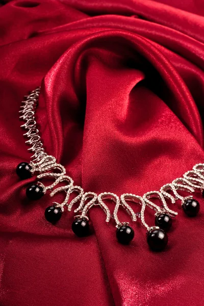 Schwarze Perlen auf rotem Textil — Stockfoto