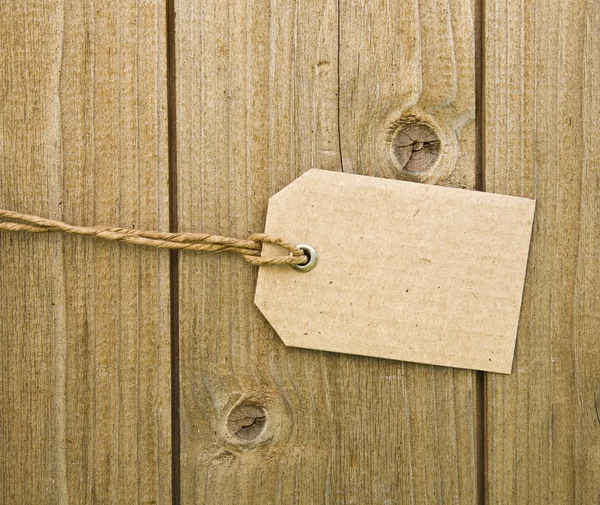 木制背景上空白棕色纸板标签 免版税图库照片